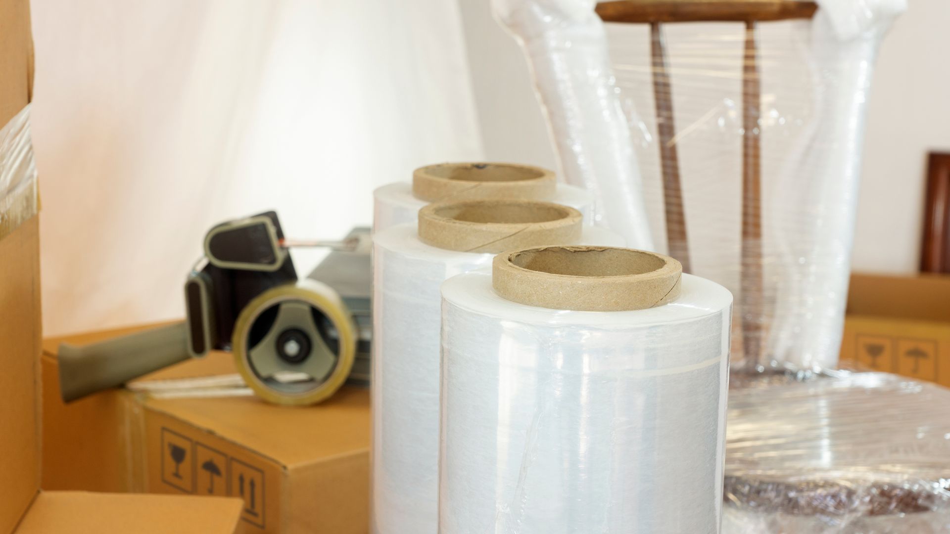 A row of rolls of plastic wrap sitting on top of cardboard boxes.