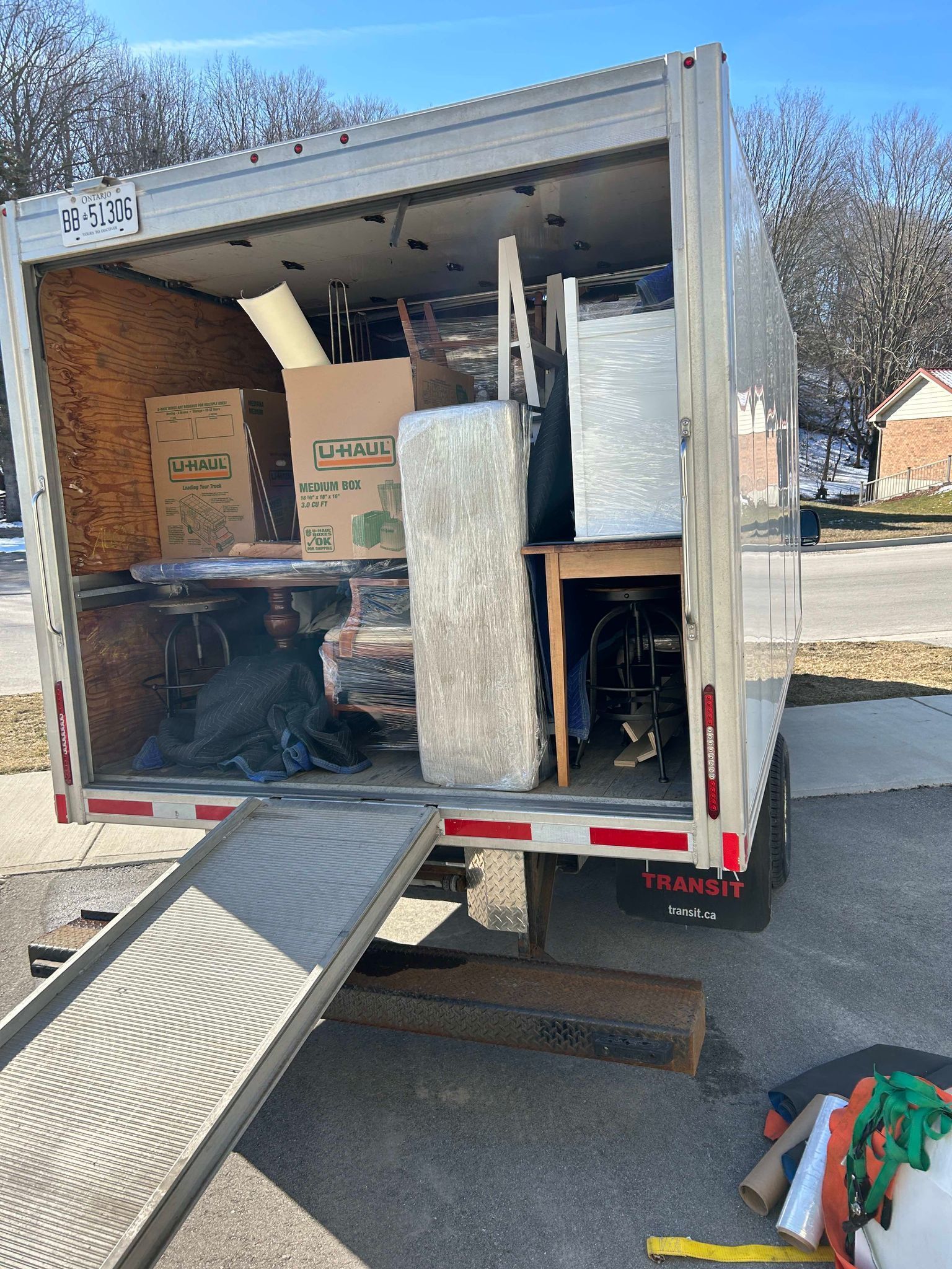 A moving truck filled with boxes and furniture is parked on the side of the road.