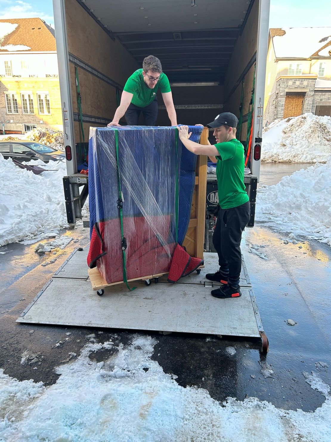 Two men are loading a piano into a truck.