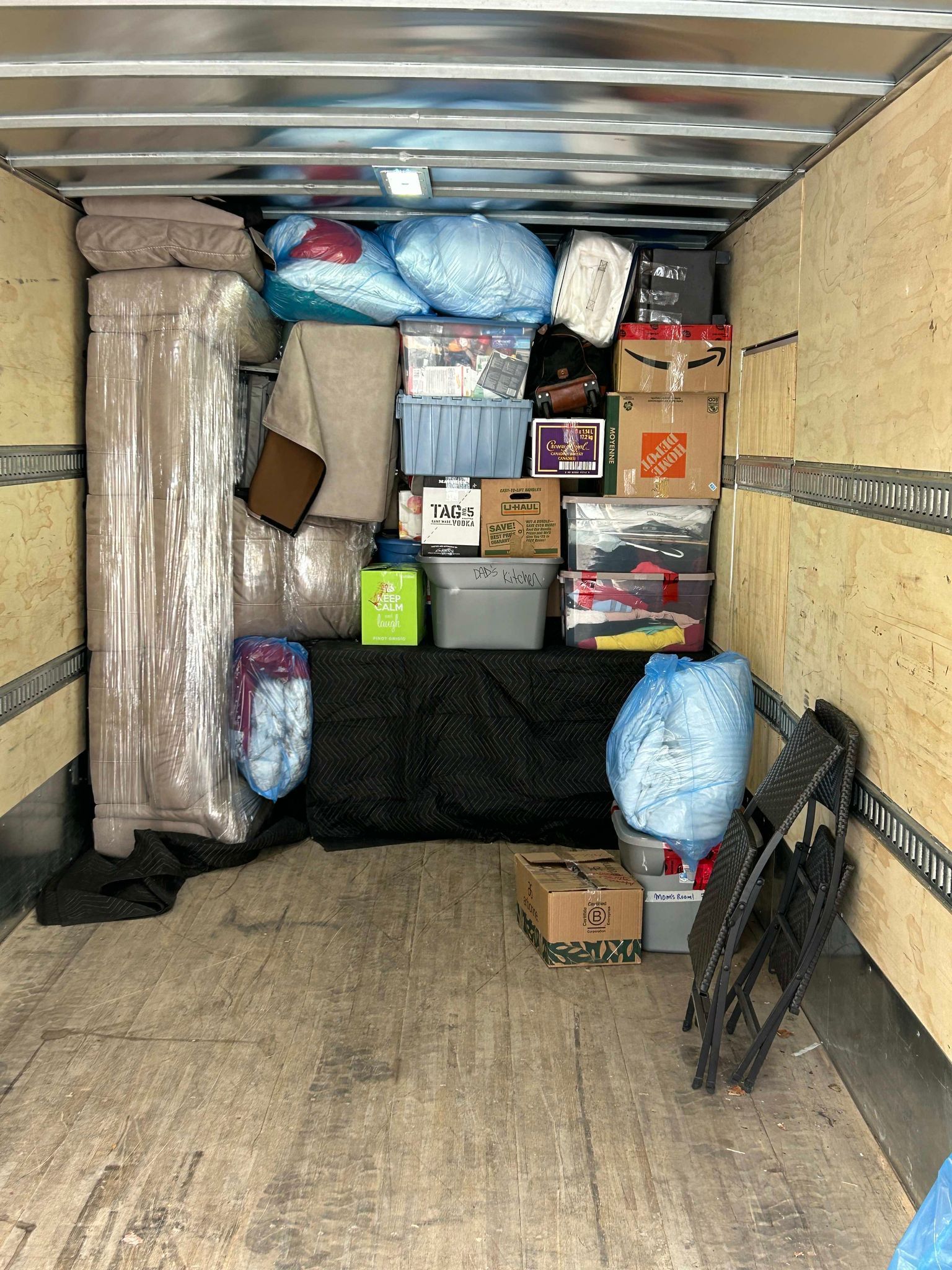 The inside of a moving truck filled with boxes and furniture.