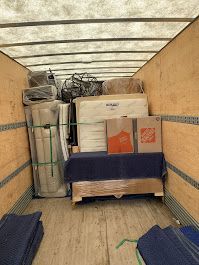 The inside of a moving truck filled with furniture and boxes.