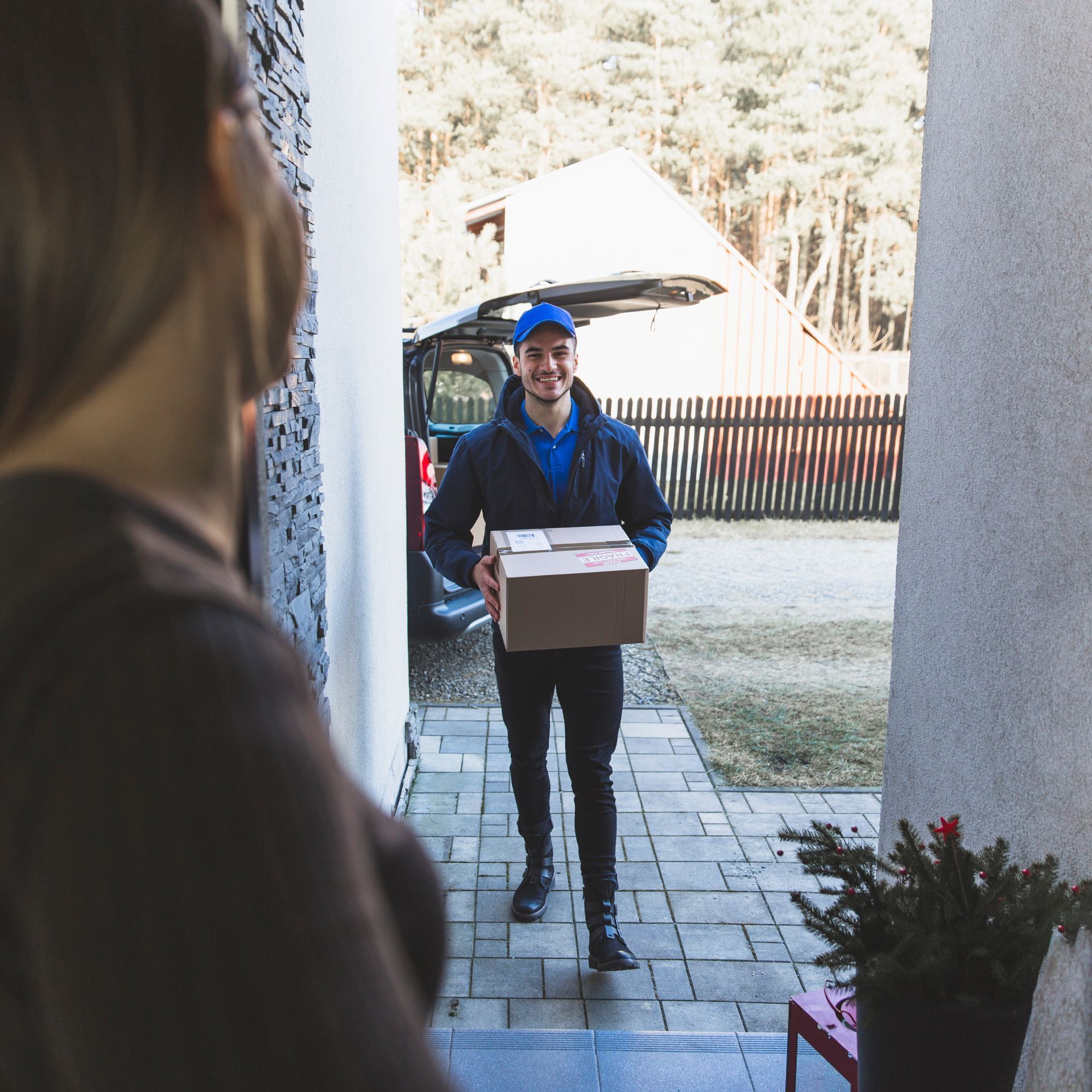 A man in a blue hat is carrying a cardboard box