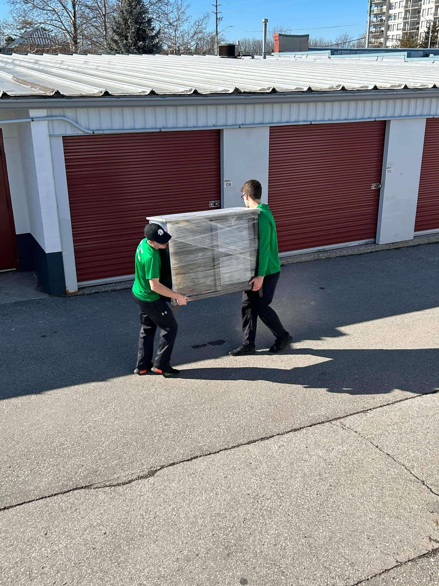 Two men are carrying a large piece of wood down a street.