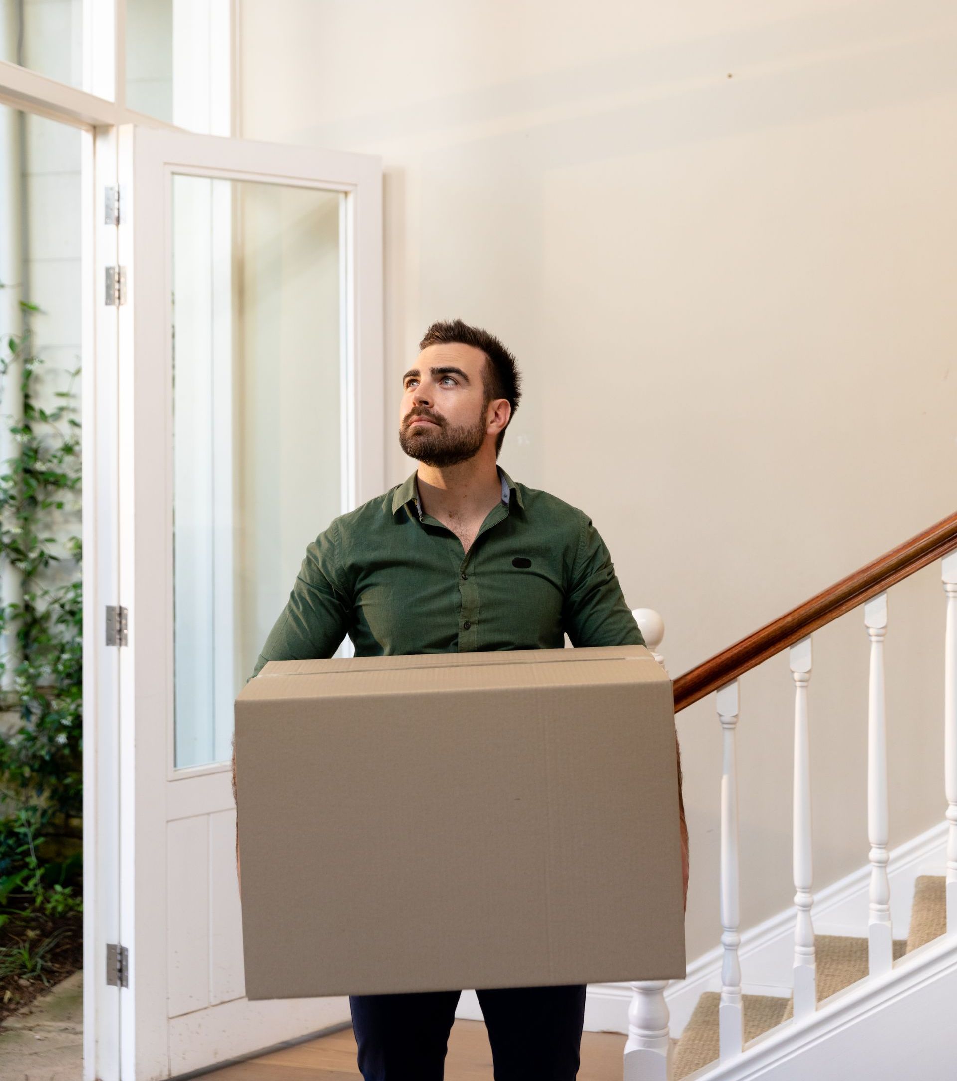 A man is carrying a cardboard box up a set of stairs.