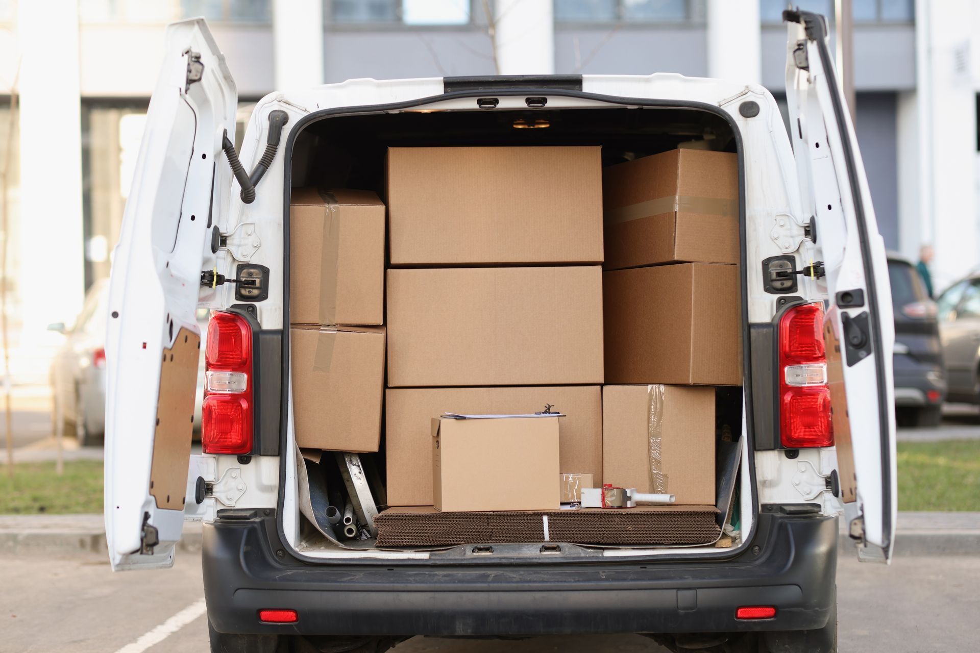 The back of a white delivery van filled with cardboard boxes.