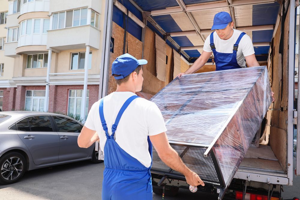 Two men are carrying a refrigerator up a set of stairs