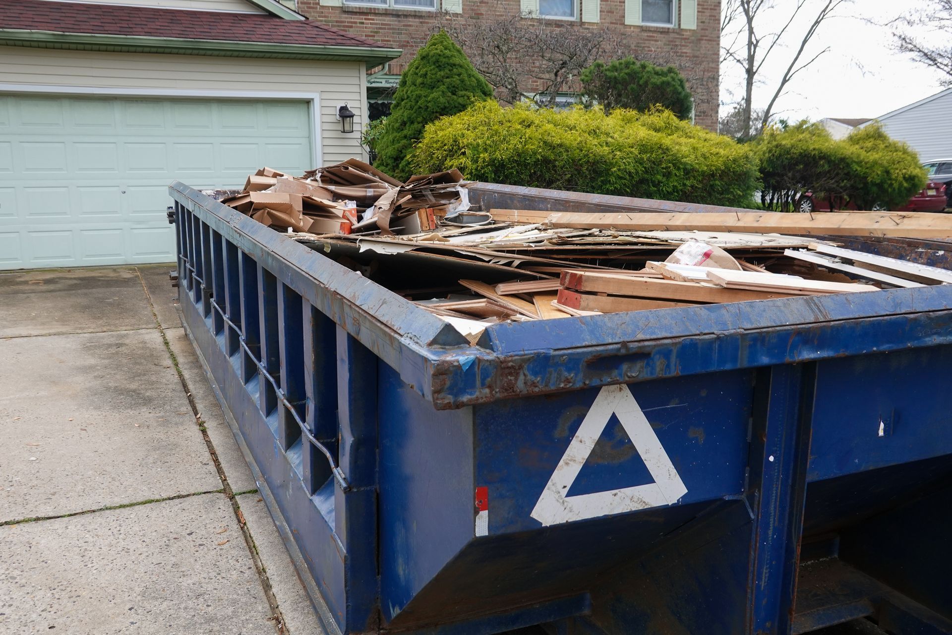 A blue dumpster with a white triangle on the side of it