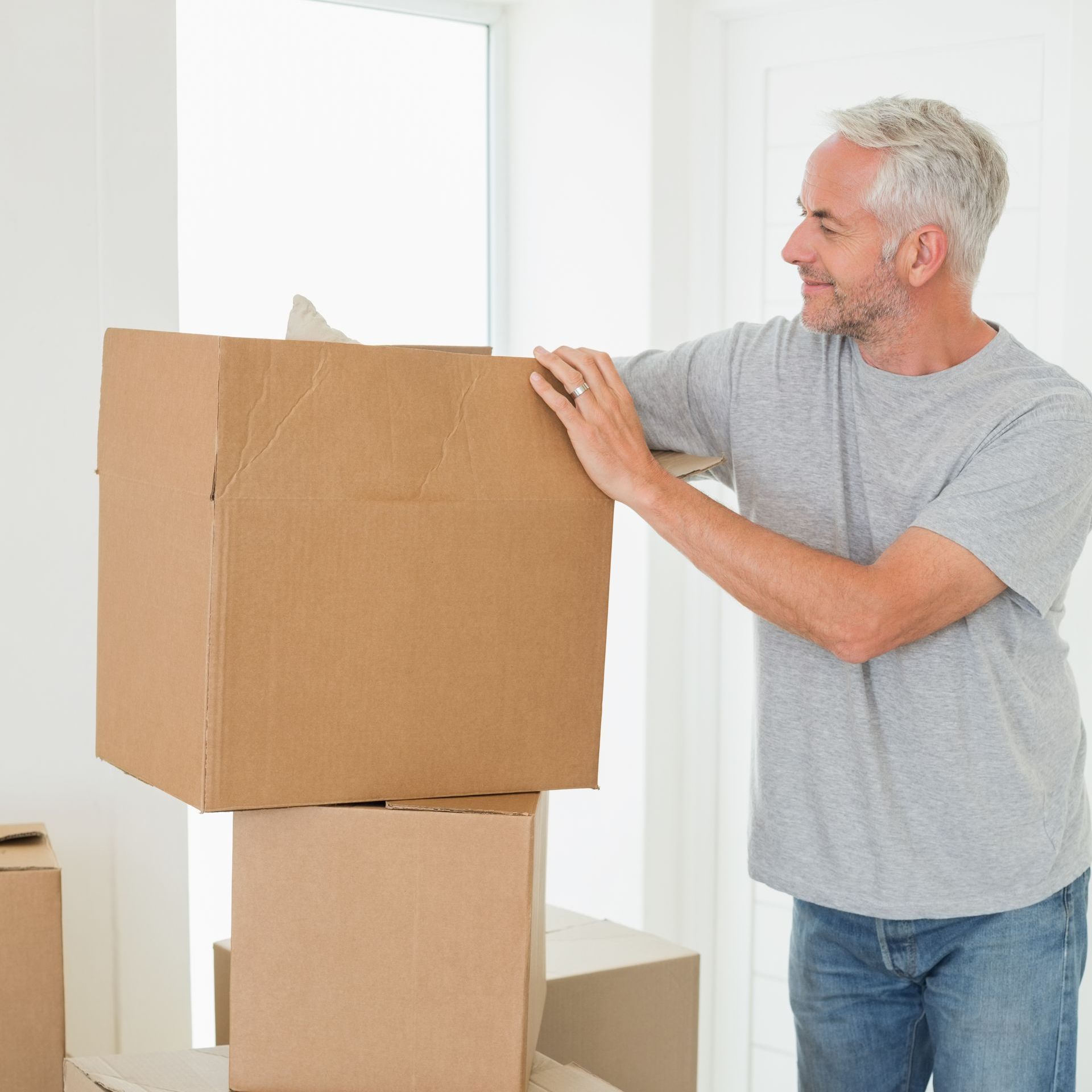 A man is standing next to a pile of cardboard boxes.