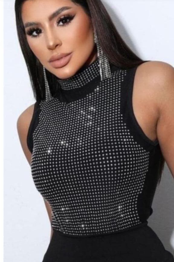 Mujer con top negro brillante y pendientes plateados.