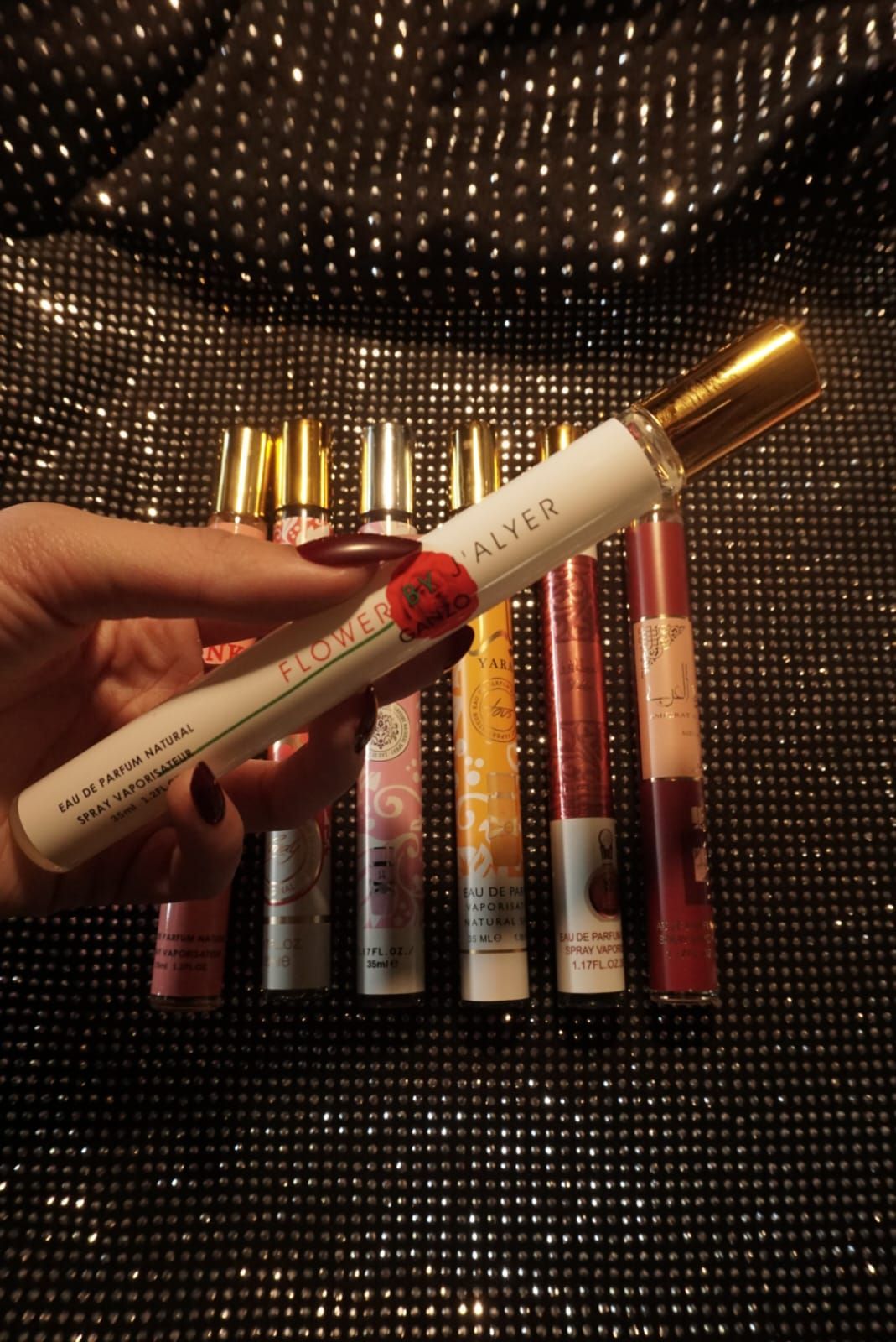 Mujer abriendo una riñonera negra, dejando ver su lápiz labial. Lleva un top de lentejuelas y vaqueros.