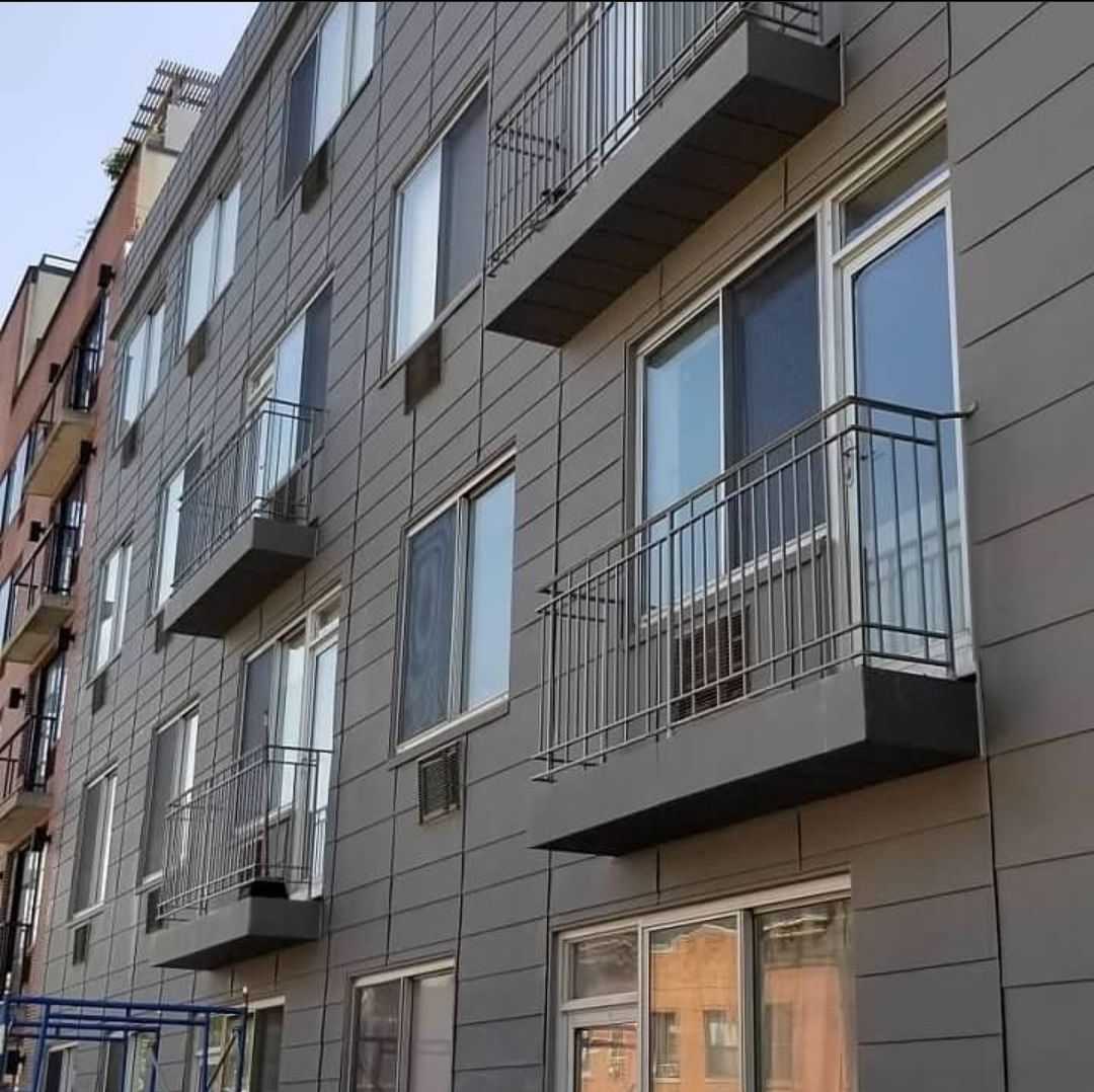 A white house with a balcony and a fence in front of it.