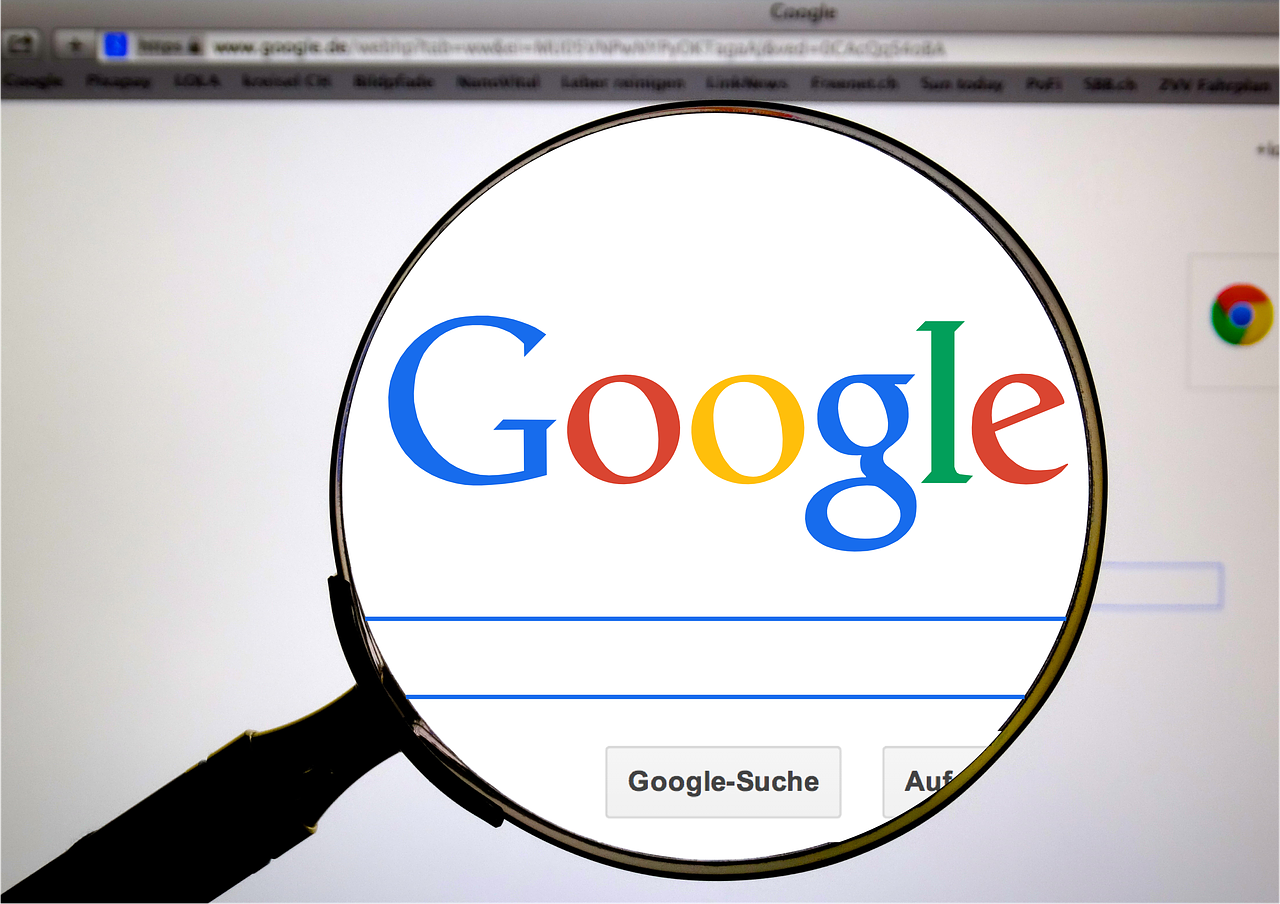 A magnifying glass shows the google logo on a computer screen
