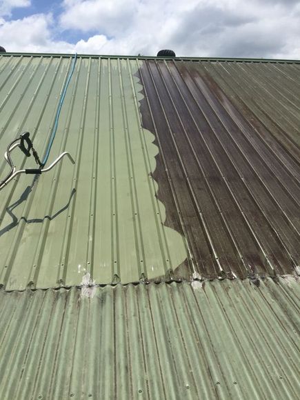 A green metal roof is being painted brown.