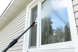 A person is cleaning a window with a high pressure washer.