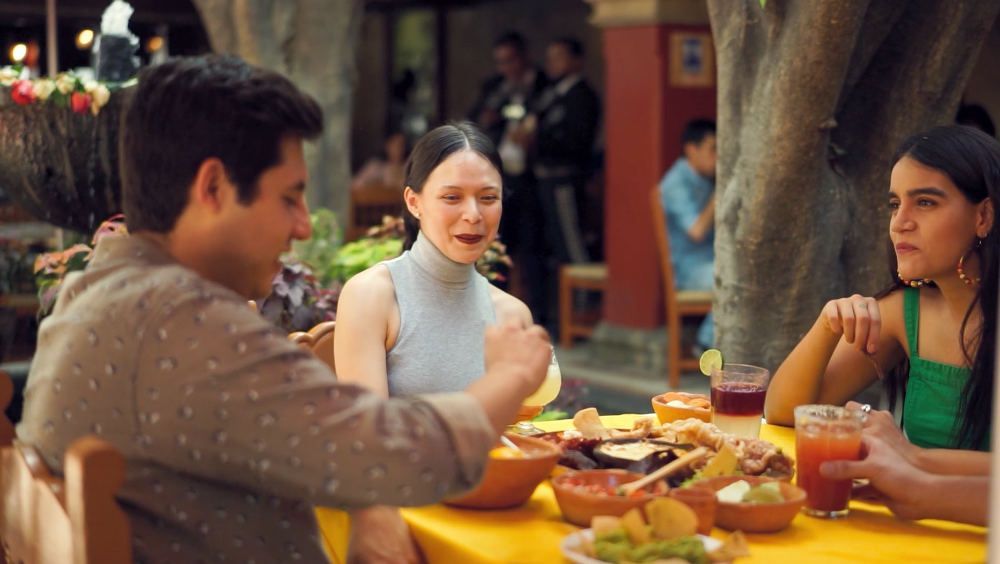 A group of people are sitting at a table eating food at a client's restaurant.