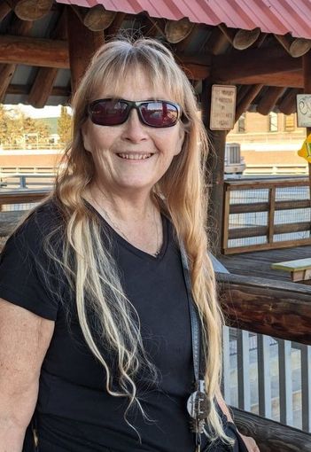 Sandy Gale wearing sunglasses and a black shirt is smiling for the camera.