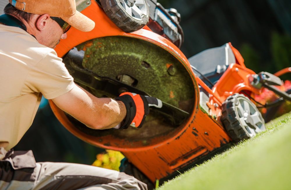 A Man Is Cutting Grass With An Orange Lawn Mower — Rocky Small Motor Service In Rockhampton, QLD