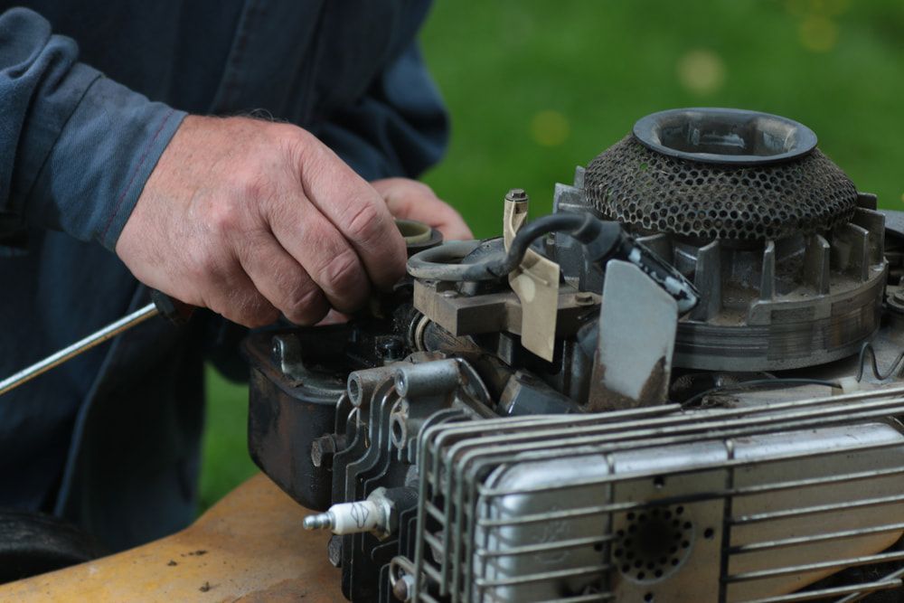 A Man Is Working On A Lawn Mower Engine — Rocky Small Motor Service In Rockhampton, QLD