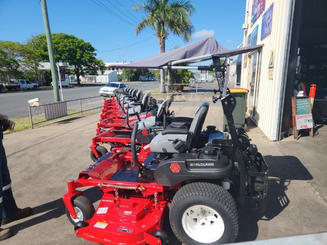 A Row Of Red Lawn Mowers Are Parked Outside Of A Building — Rocky Small Motor Service In Rockhampton, QLD