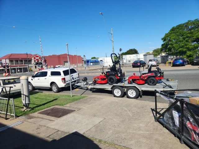 Two Lawn Mowers Are On A Trailer Parked On The Side Of The Road — Rocky Small Motor Service In Rockhampton, QLD