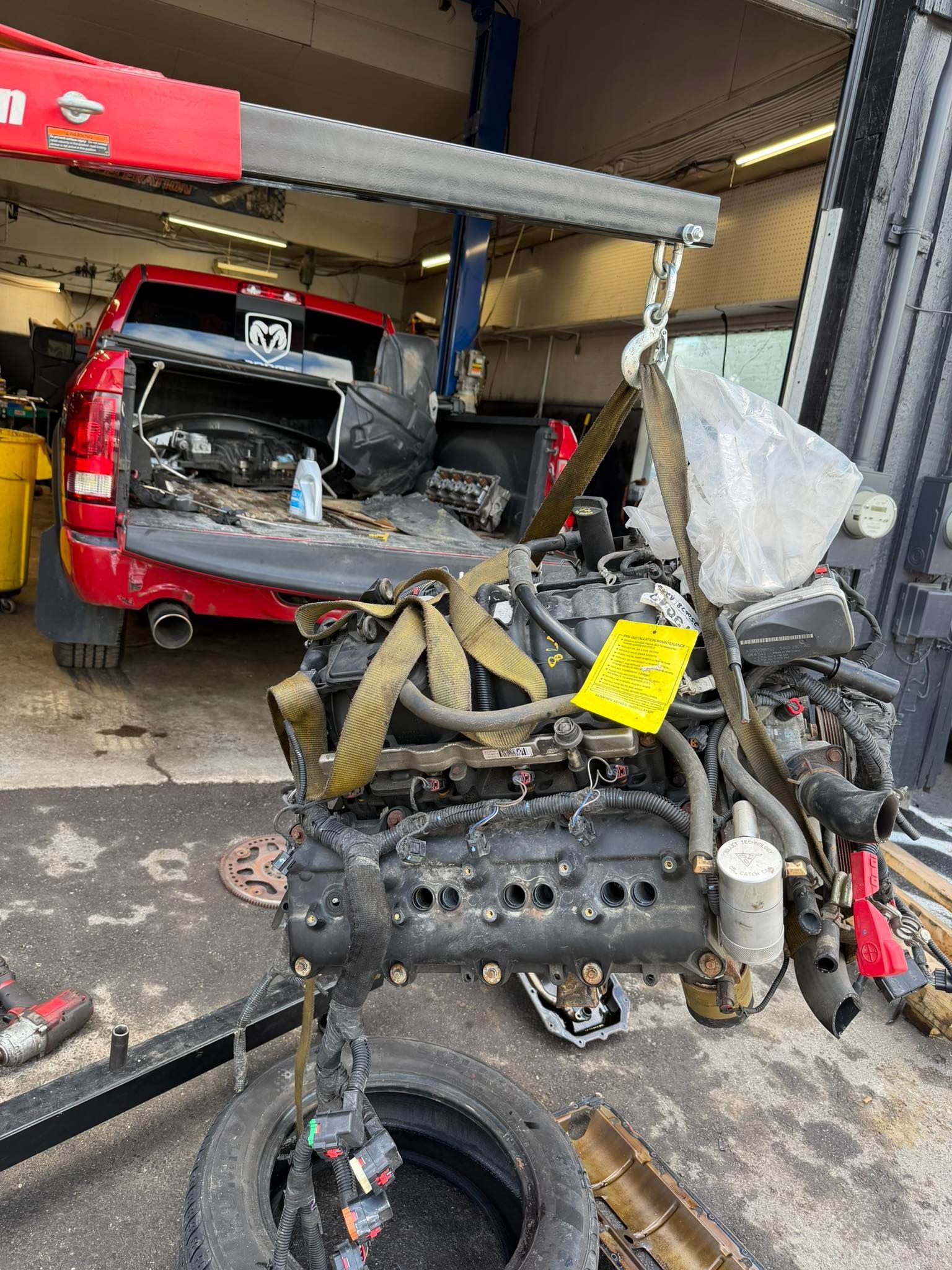 Crash-damaged vehicle in garage with detached engine parts and a smashed front end