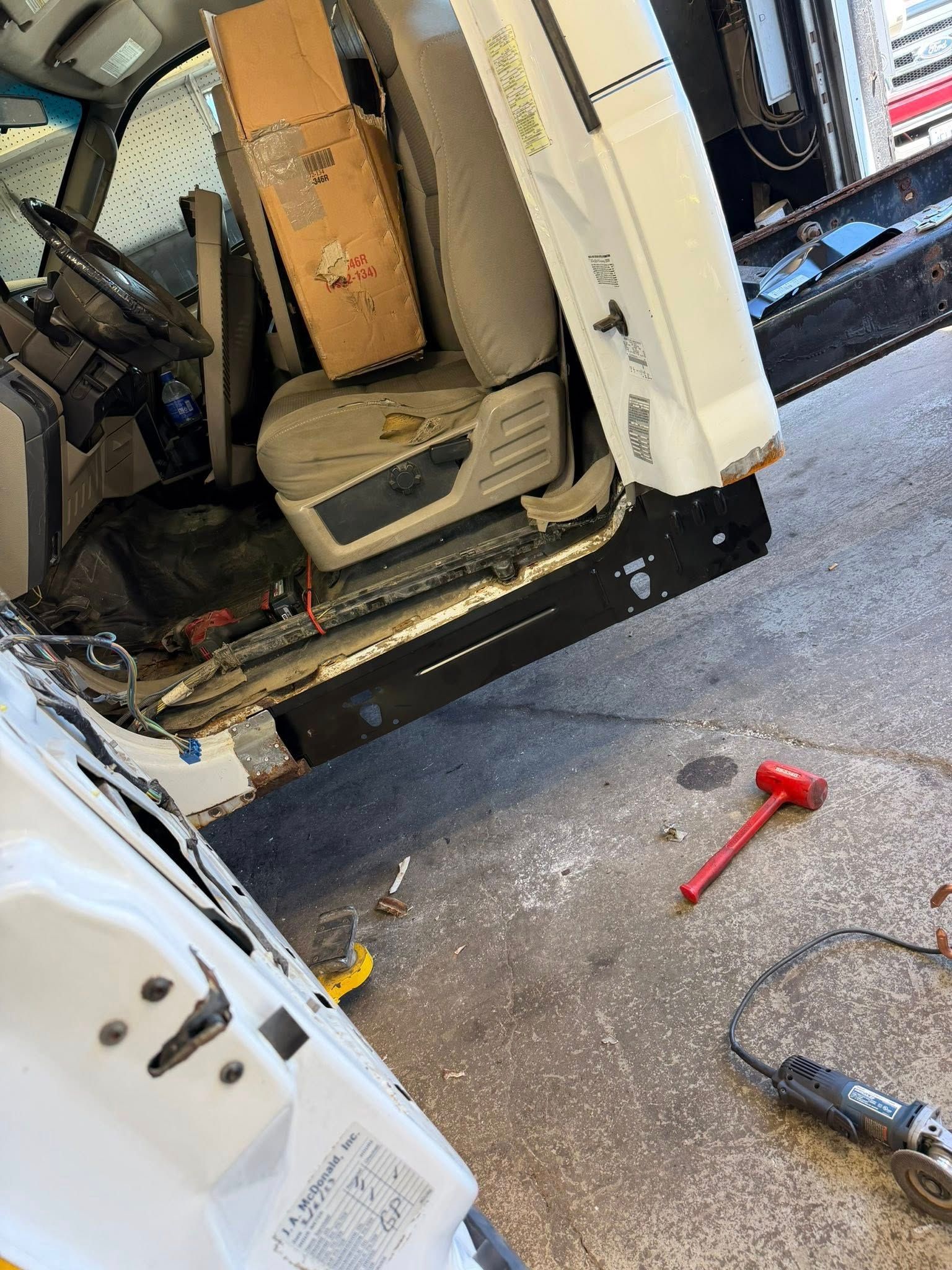 Open van with exposed beige interior, tools on concrete floor, and a red hammer nearby.