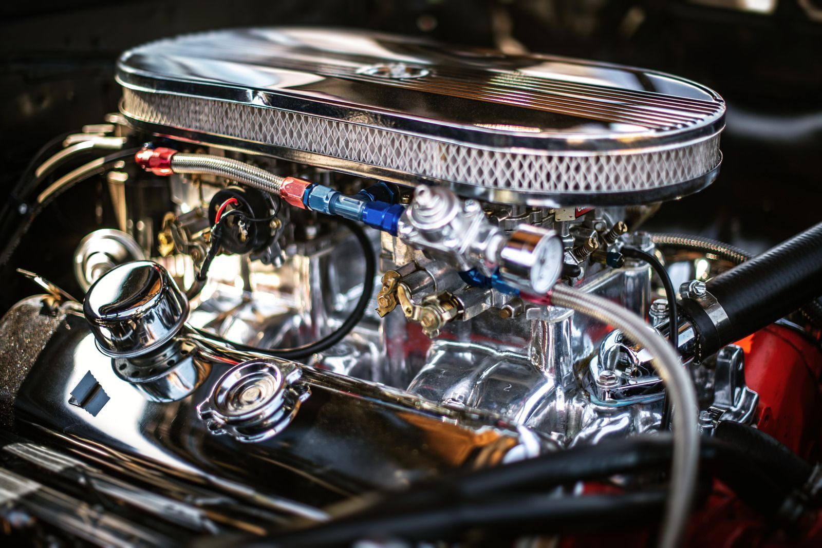 Chrome car engine with polished air intake and visible hoses under the hood