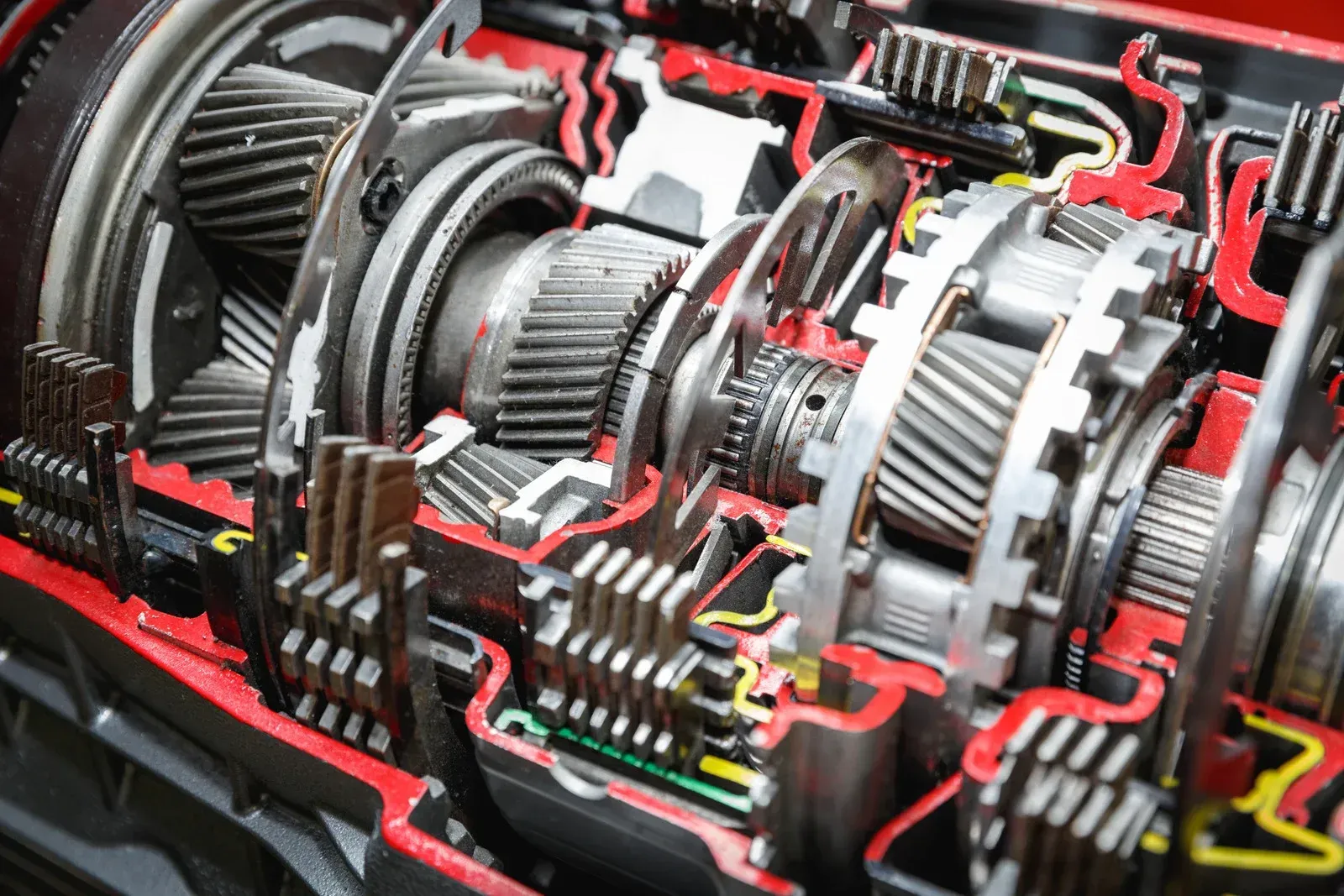 Close-up of a cutaway mechanical gearbox with interlocking metal gears and red wiring details