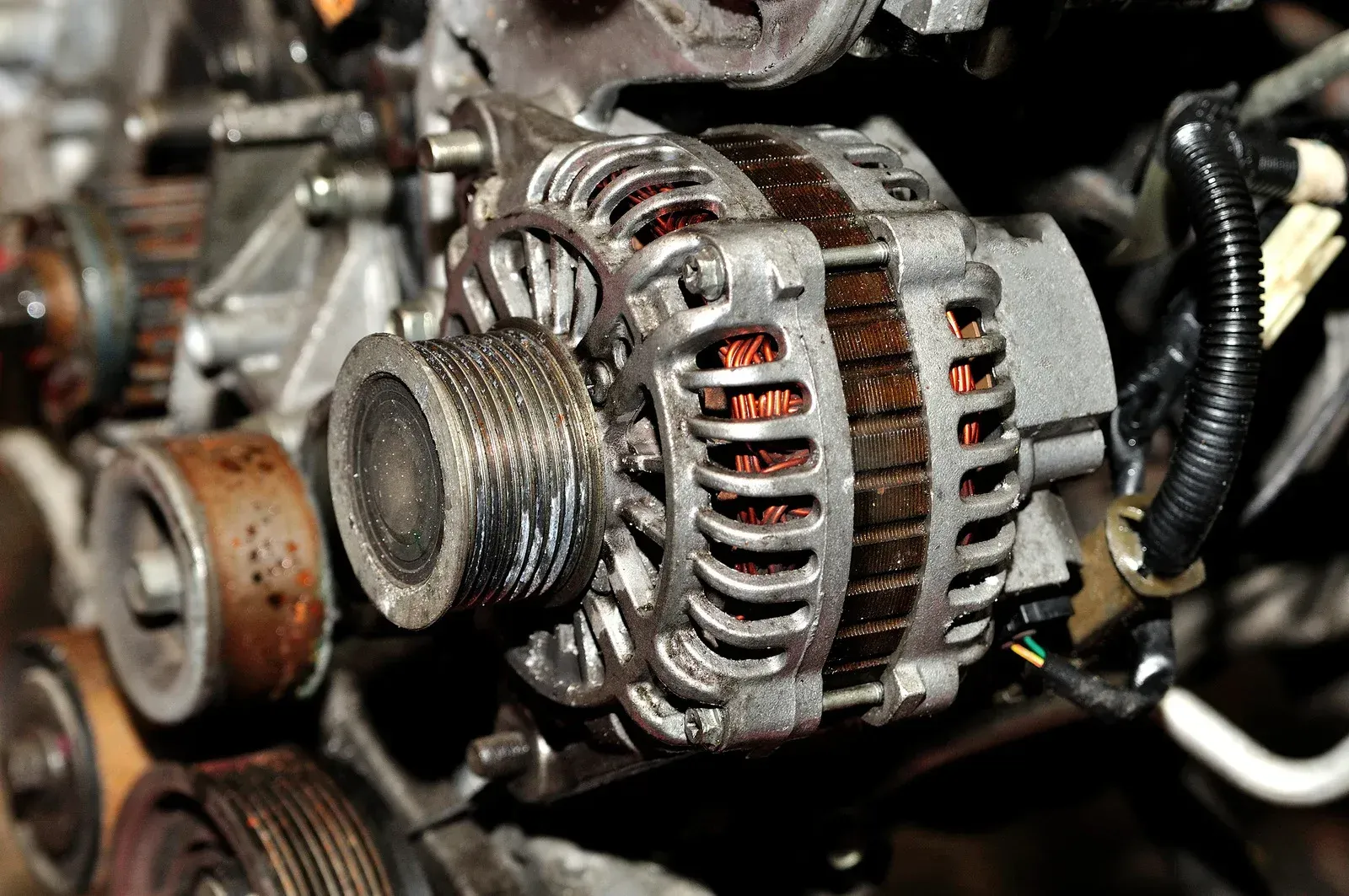 Car battery jump-start setup with red and black clamps in a car engine bay.