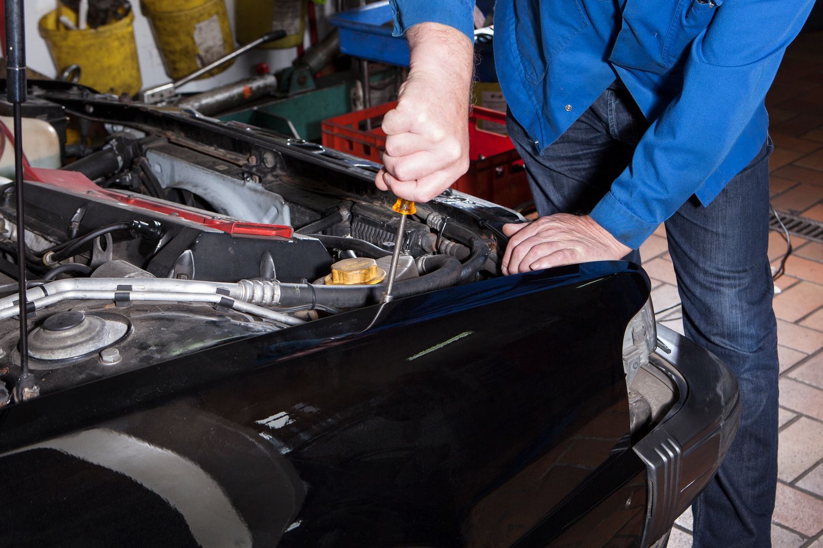 Mechanic working under the hood of a black car in a garage