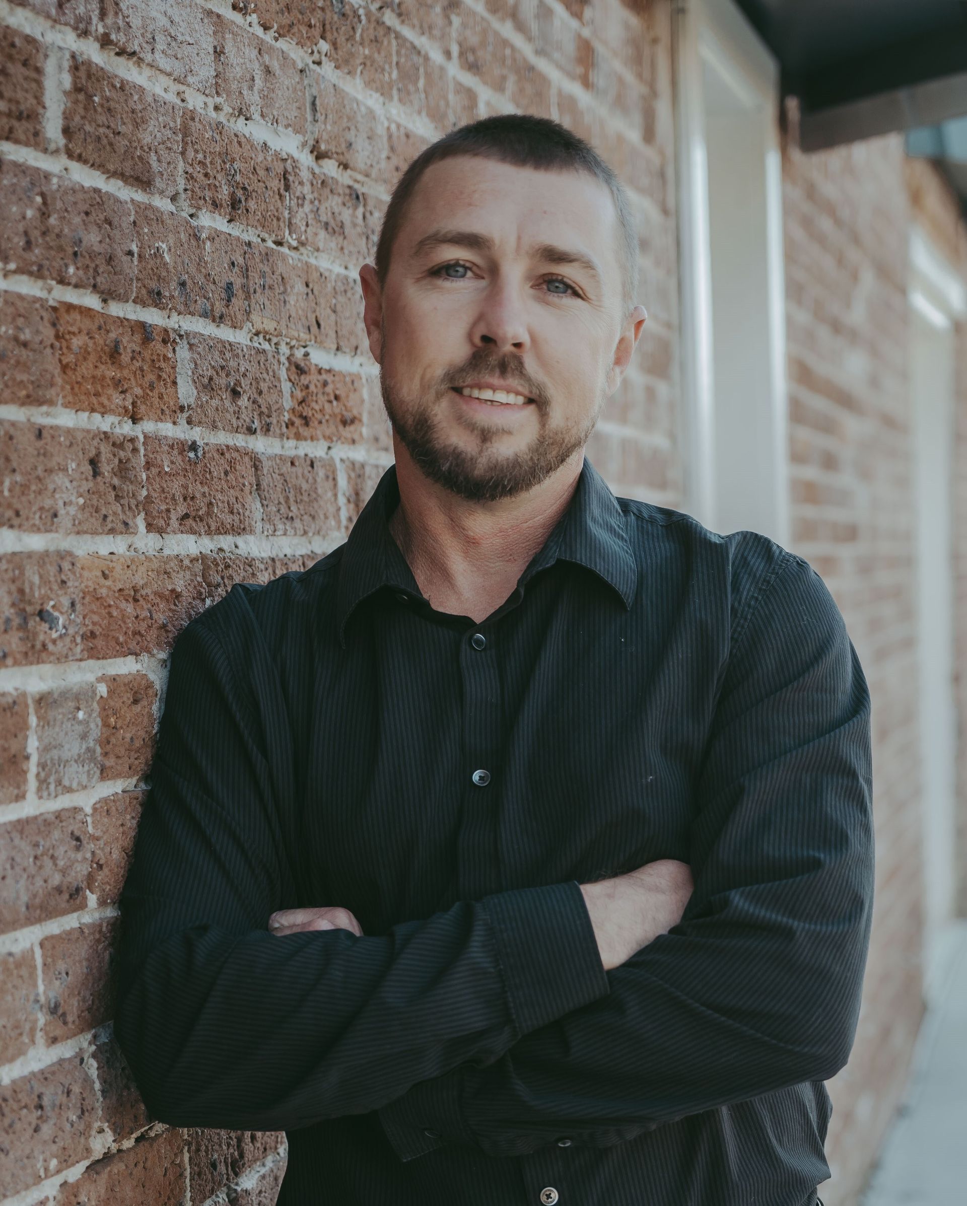 A woman is sitting at a desk with a laptop and a vase of flowers.