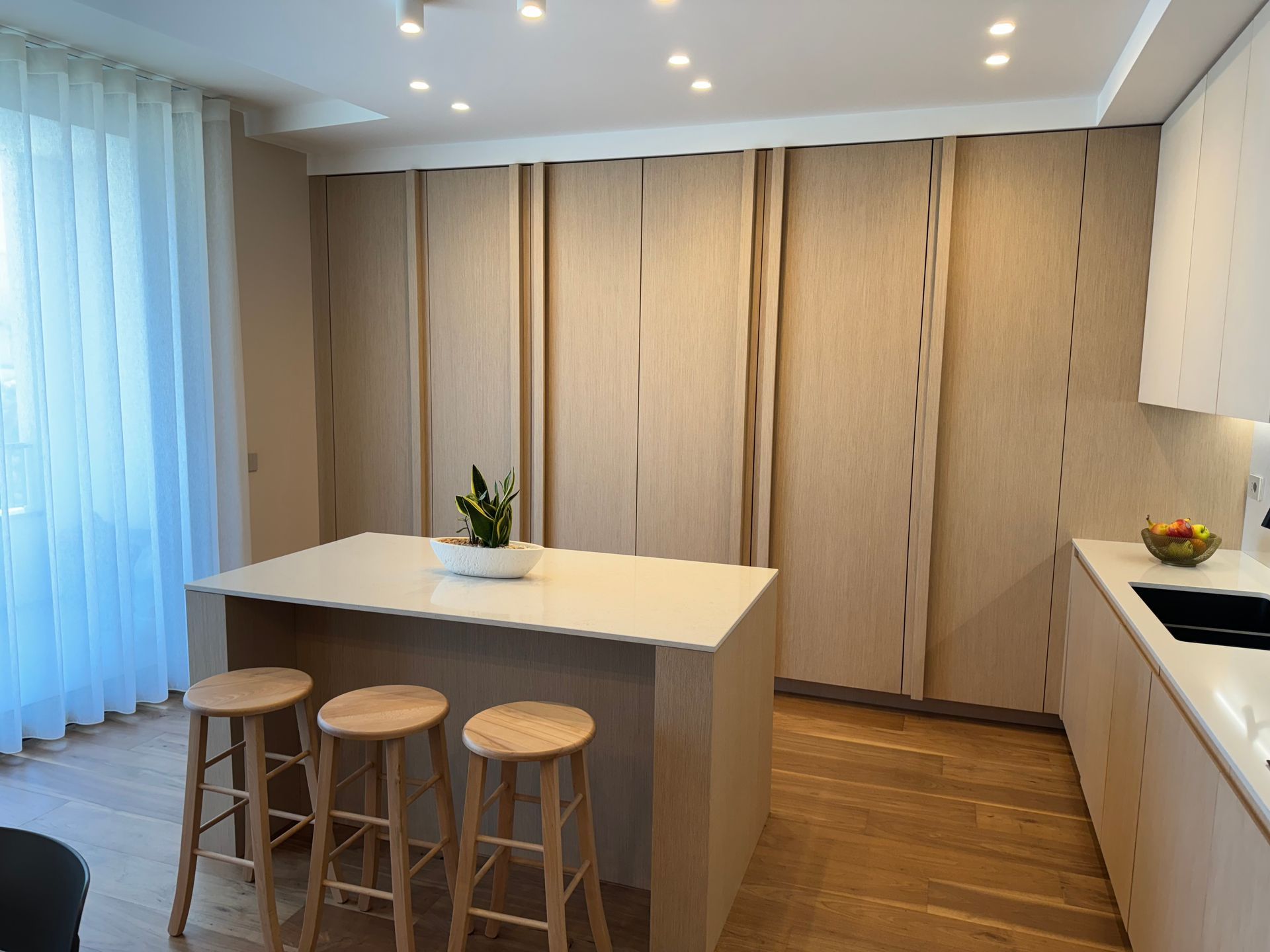 Una cucina con una grande isola, sgabelli e un lavello.