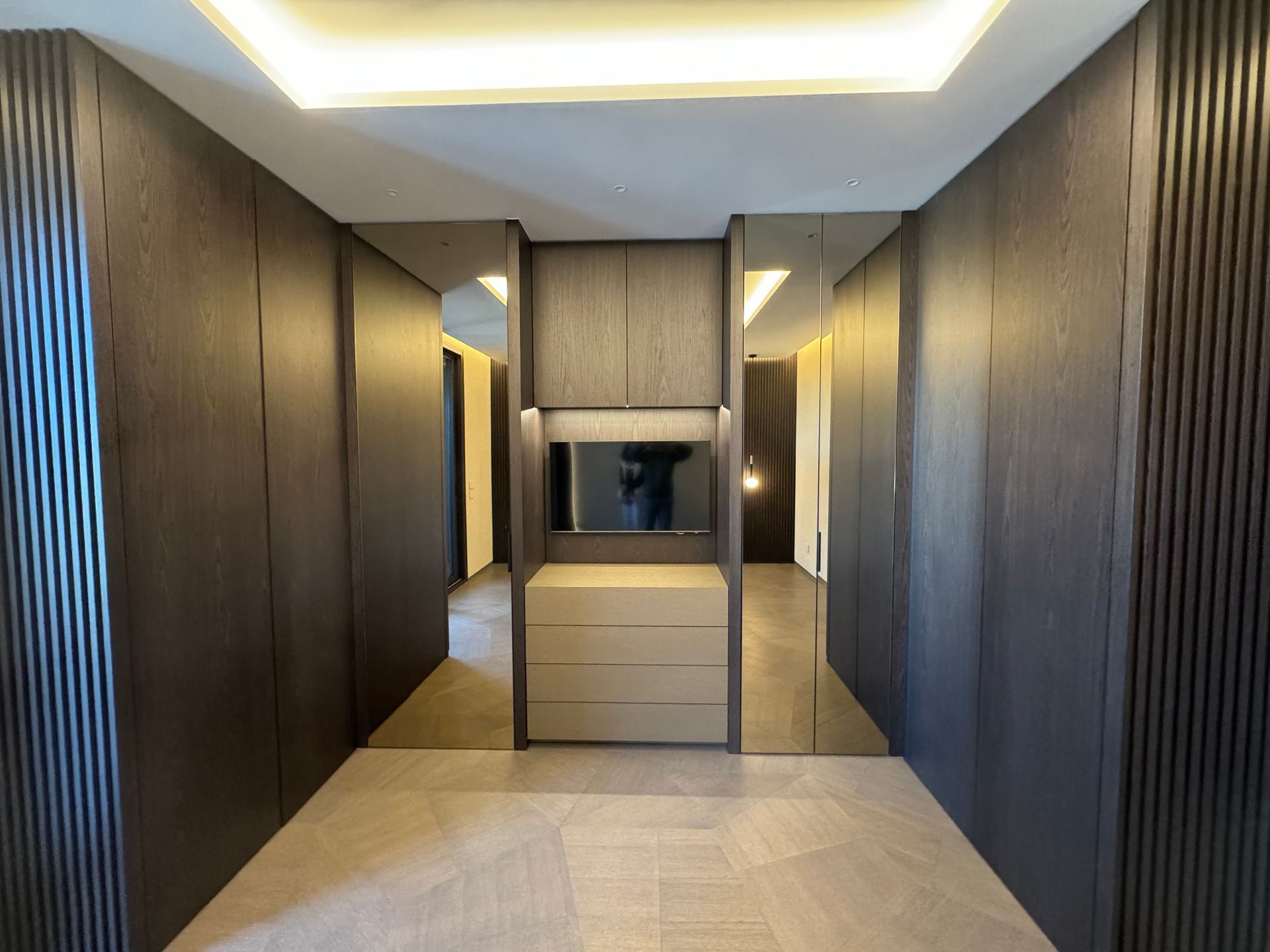 Un corridoio con una cassettiera e un televisore a parete.