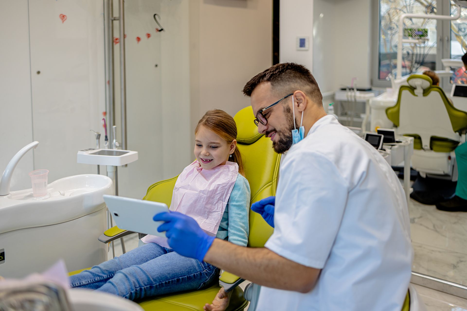 A young girl in a dentist chair with a man, showcasing family dentistry and comfort for children.