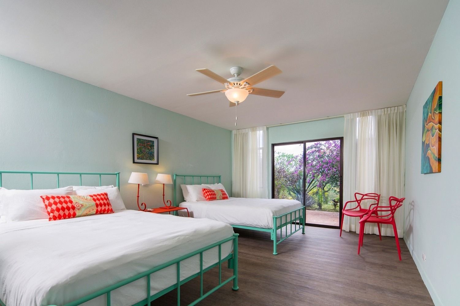 A bedroom with a large bed , chair , sliding glass doors and a ceiling fan.