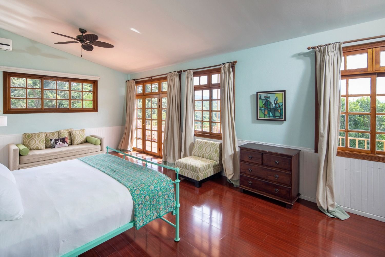 A bedroom with a large bed , chair , sliding glass doors and a ceiling fan.
