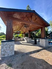 A pavilion with a wooden roof and a ceiling fan.