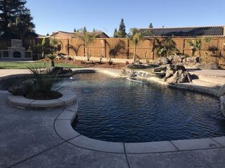 A large swimming pool in a backyard with a wooden fence surrounding it.