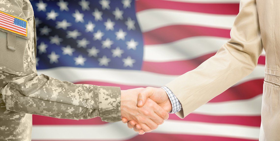 US service member and professional shaking hands in front of American flag
