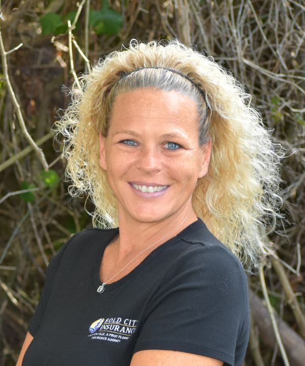 A woman with blonde hair is wearing a black shirt and smiling.