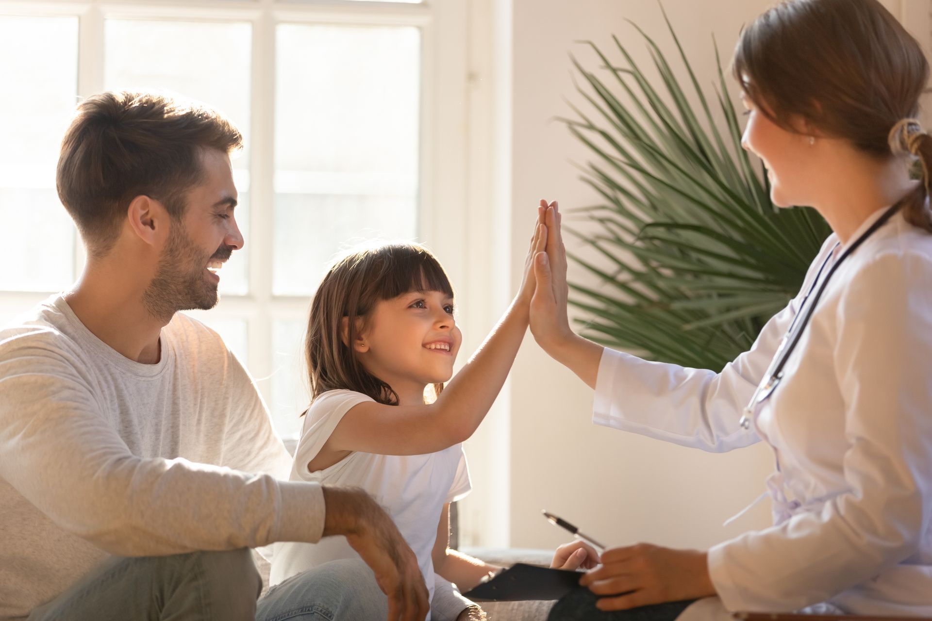 A little girl is giving a high five to a doctor.