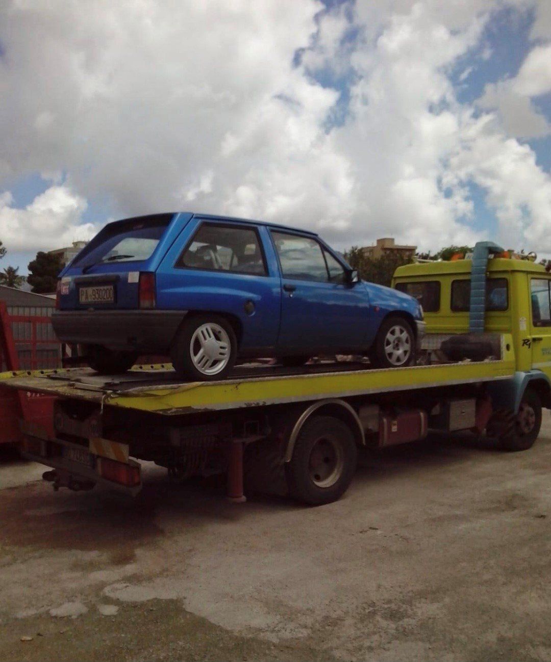 Un'auto blu è parcheggiata sopra un carro attrezzi giallo