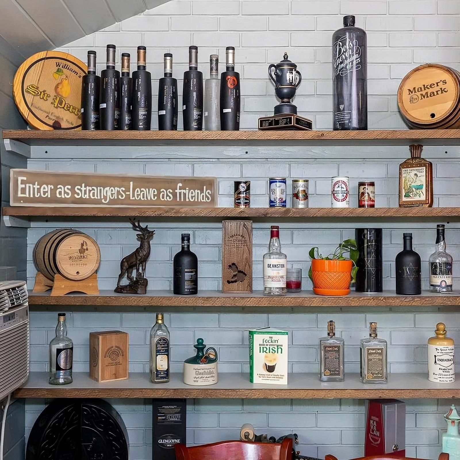 Shelves filled with bottles and a sign that says enter as strangers leave as friends