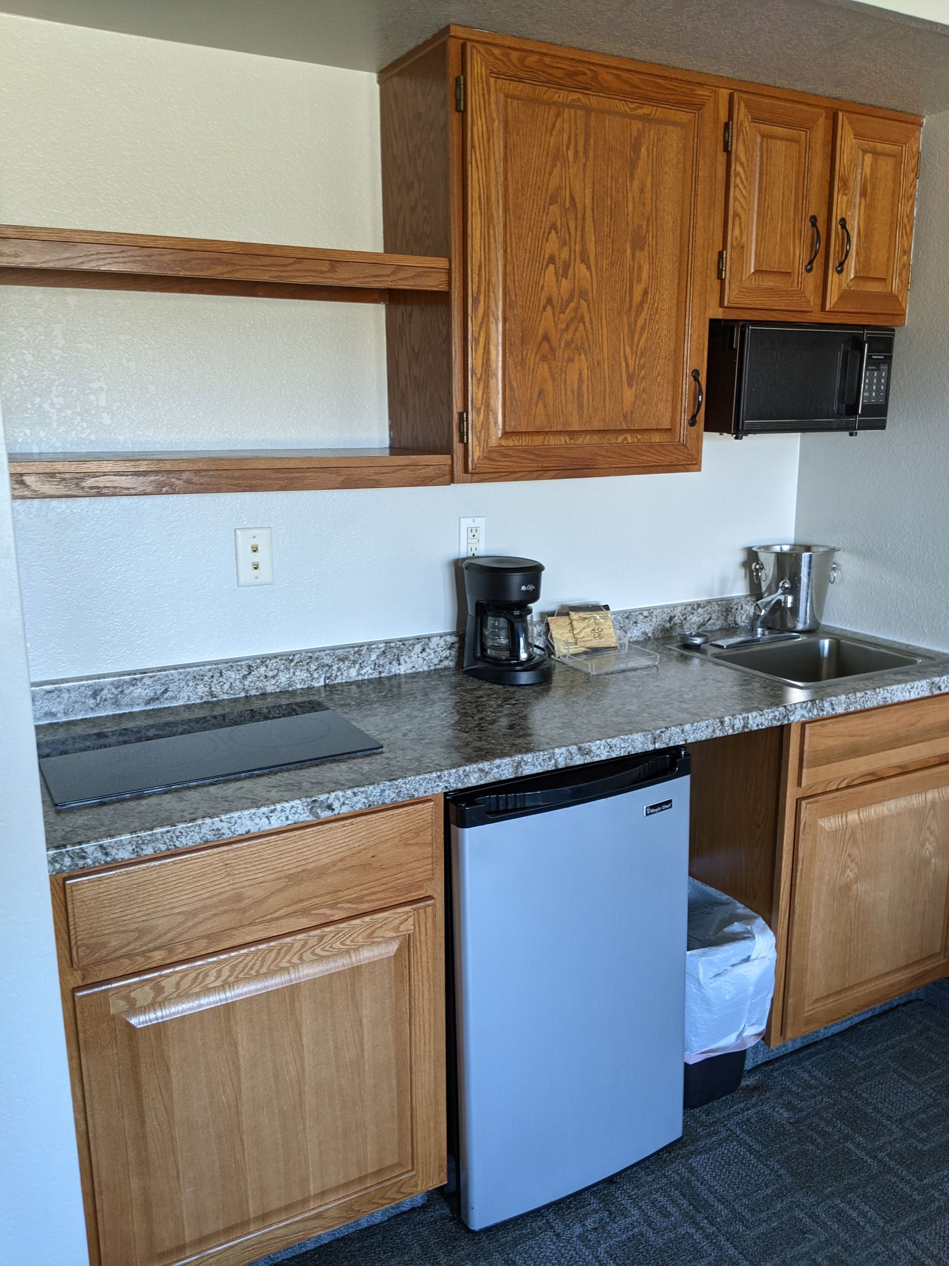 A kitchen with wooden cabinets , a stove , a sink , and a refrigerator.