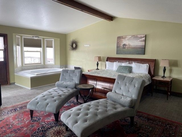 A bedroom with a large bed and a jacuzzi tub