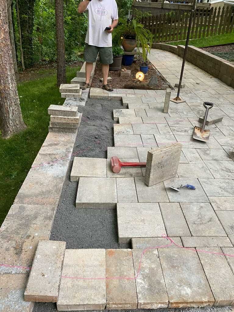 A man is standing next to a pile of bricks on a patio.