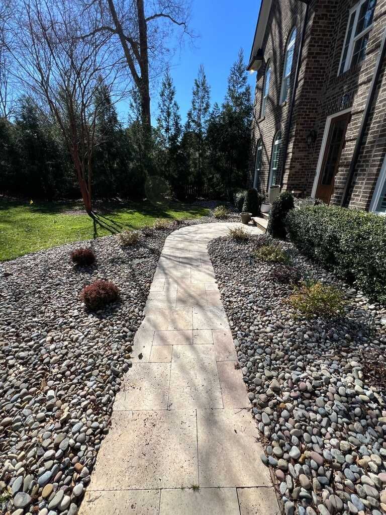 A stone walkway leading to a house surrounded by rocks.
