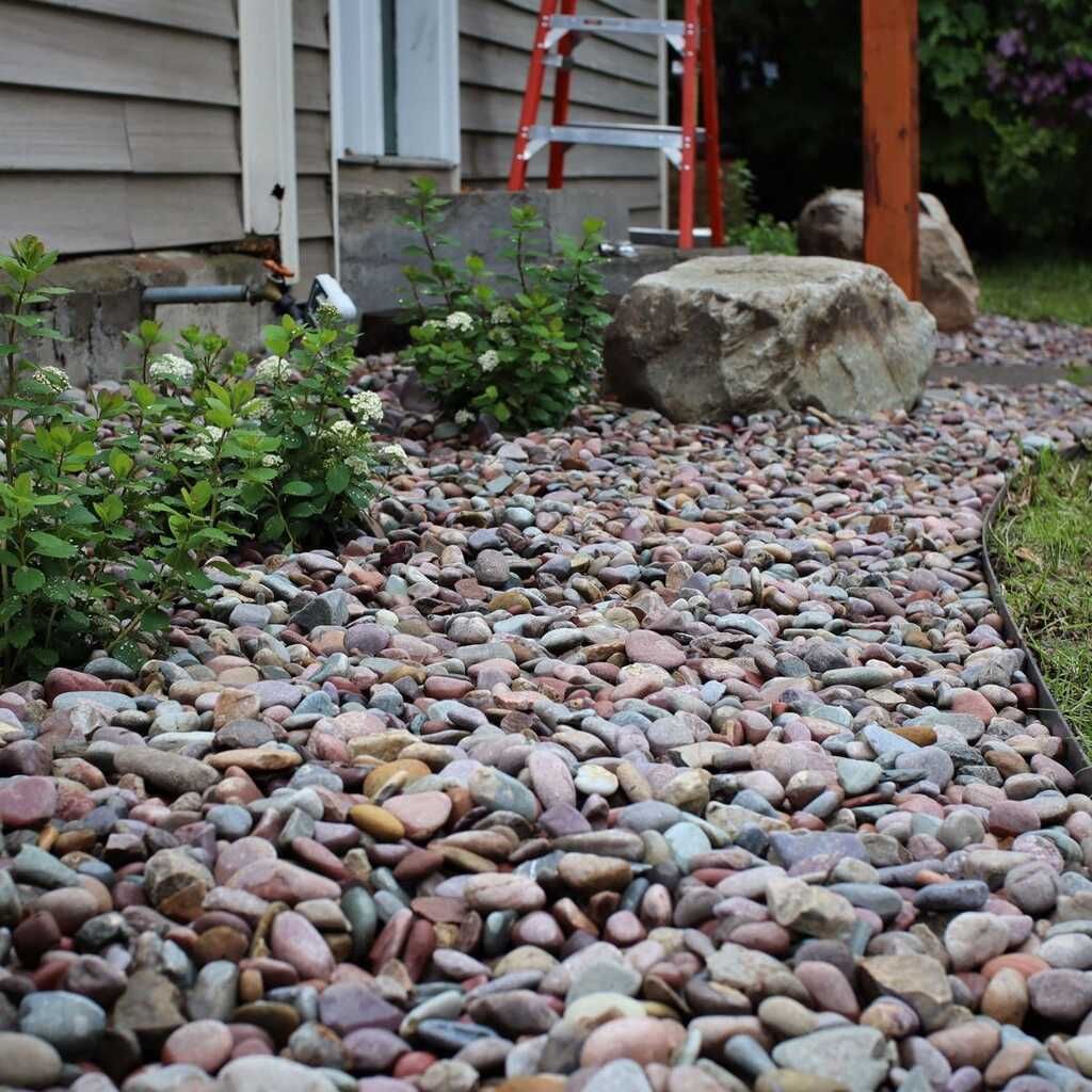 A walkway filled with rocks and plants in front of a house.