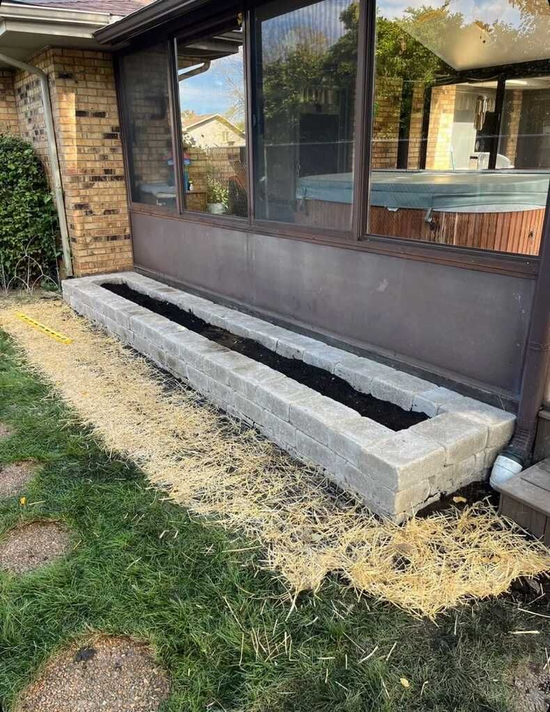 A concrete planter is being built in front of a house.