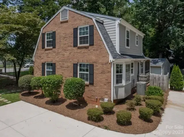 A large brick house with black shutters is for sale.